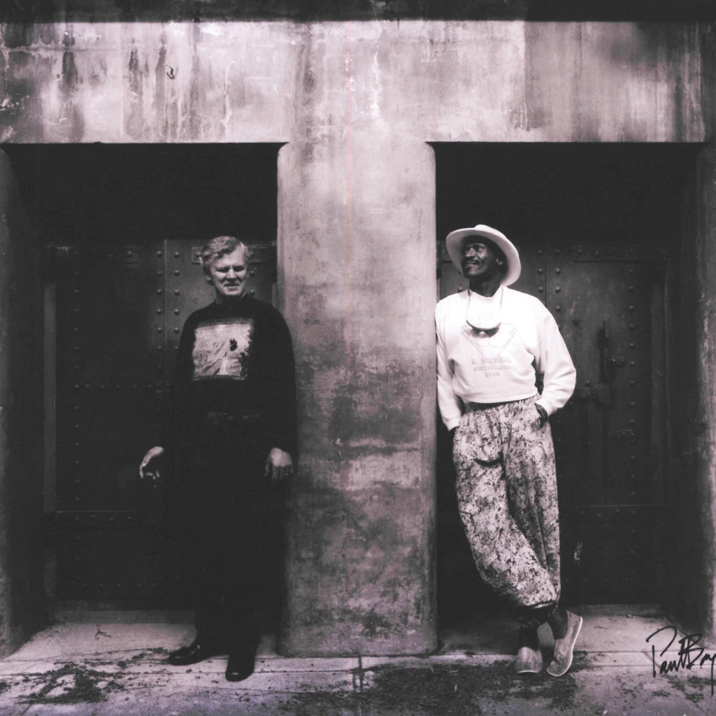 Doc Watson and Taj Mahal in front of a bunker in Fort Worden State Park in 1990, photo by Paul Boyer.