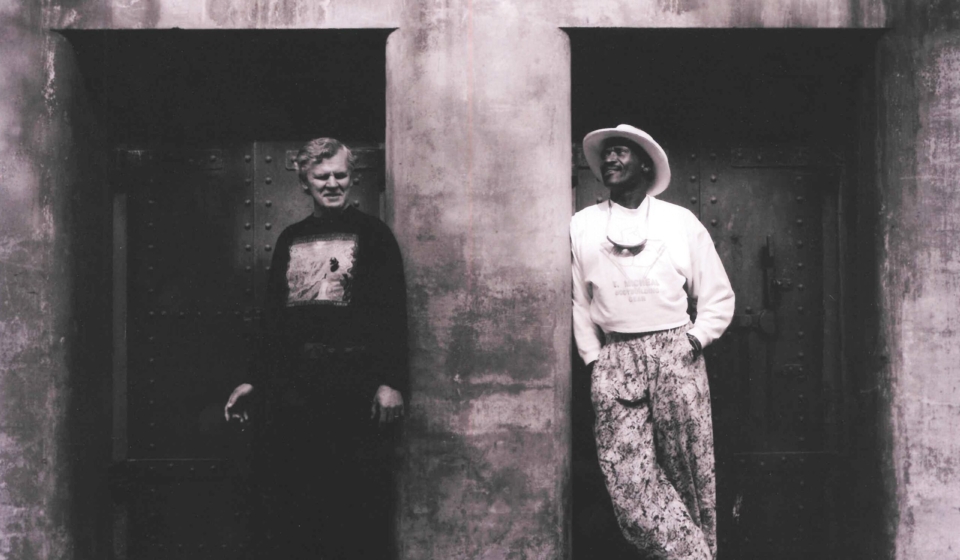 Doc Watson and Taj Mahal in front of a bunker in Fort Worden State Park in 1990, photo by Paul Boyer.